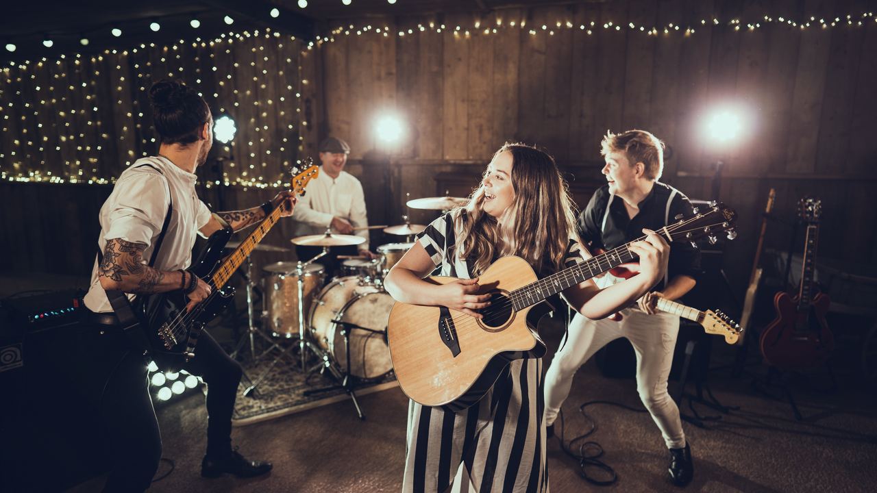The Everglow playing under festoon lights in a timber barn